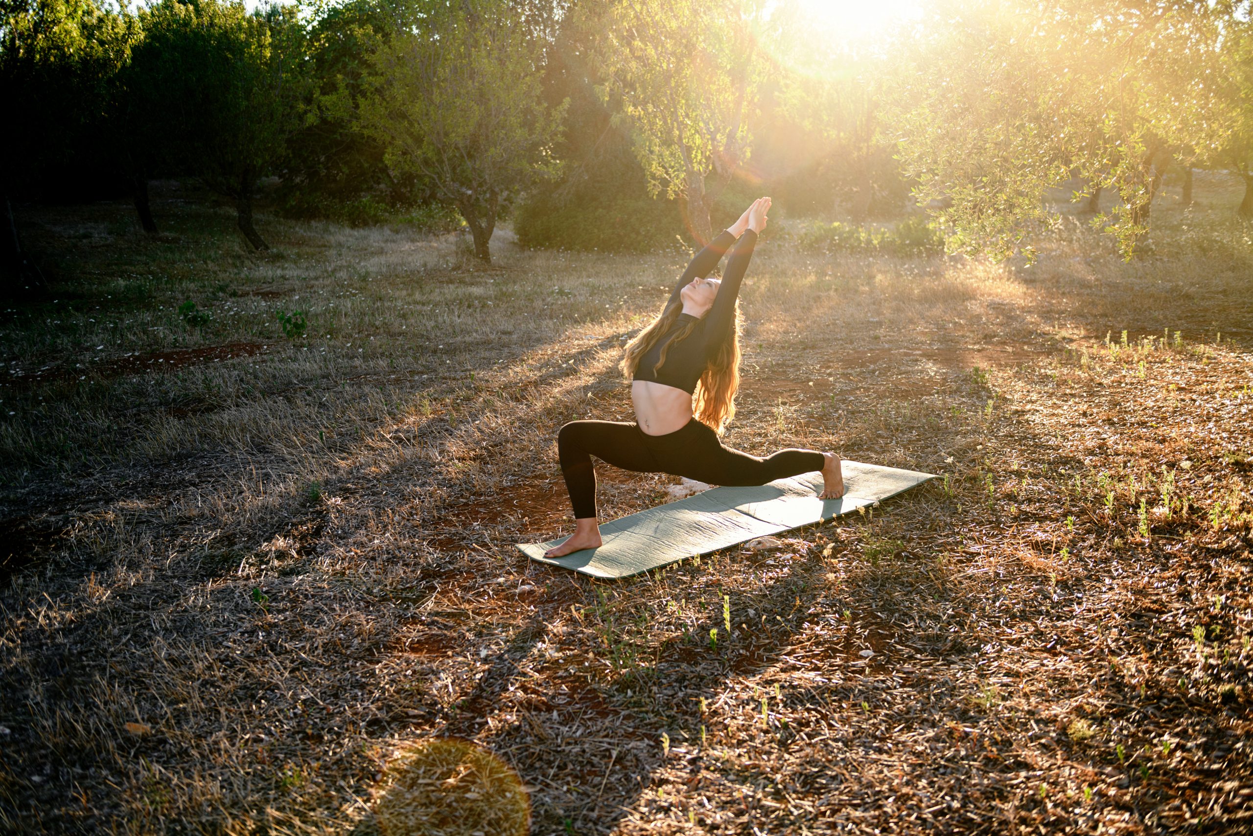 Young Girl Is Doing Yoga Strethching On The Mat On The Olive Grove At Sunset